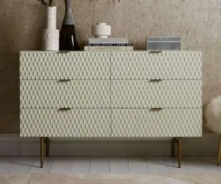 West Elm kommode med nipsting på toppen. Sæt på tæppebelagt gulv mod en almindelig soveværelsesvæg.
