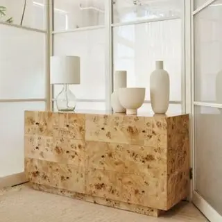 West Elm Burl Kommode, med nipsgenstande på toppen, anbragt i et spejlrum.