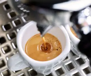 En espressomaskin som brygger en shot kaffe i et hvitt krus