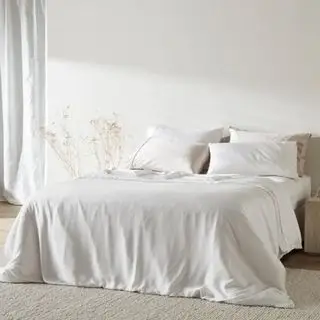 白い壁に面したベッドの上のツイル布団カバー。