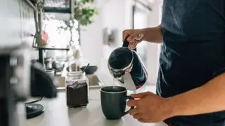 Hrnček na kávu plnený kávou z francúzskeho lisu na doske