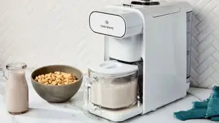 Machine à lait de noix Chefwave Milkmade en blanc sur un comptoir à côté d'un bol de céréales et d'une carafe à lait