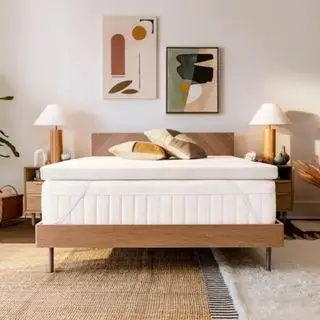 Cubrecolchón en la cama asegurado con correas y decorado con almohadas