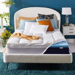 Cubrecolchón en la cama asegurado con correas y decorado con almohadas