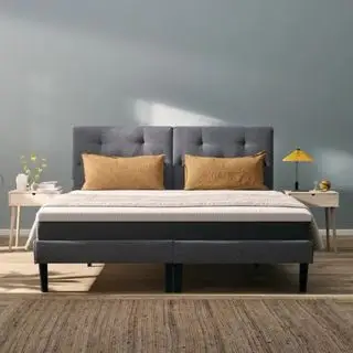 Matelas original Emma sur un lit avec oreillers contre un mur gris de la chambre.