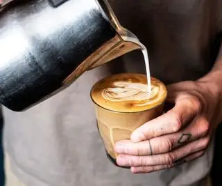 Il latte schiumato viene versato in una tazza di caffè