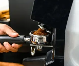 Un molinillo de café automático que muele café en un portafiltro.