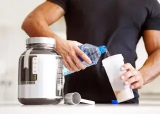 Um homem misturando água com proteína em pó em um shaker de proteína