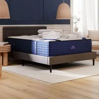 Um colchão híbrido de luxo DreamCloud em uma cama cinza em um quarto