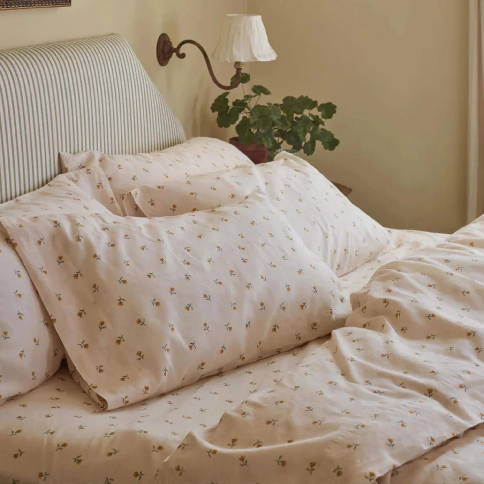 ベッドの中の子豚。白と緑の縞模様のヘッドボードが付いたベッドの上に蜂蜜の花束の寝具。' loading='lazy' title=