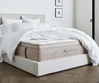 Materasso ibrido di lusso DreamCloud su un letto contro un muro bianco.