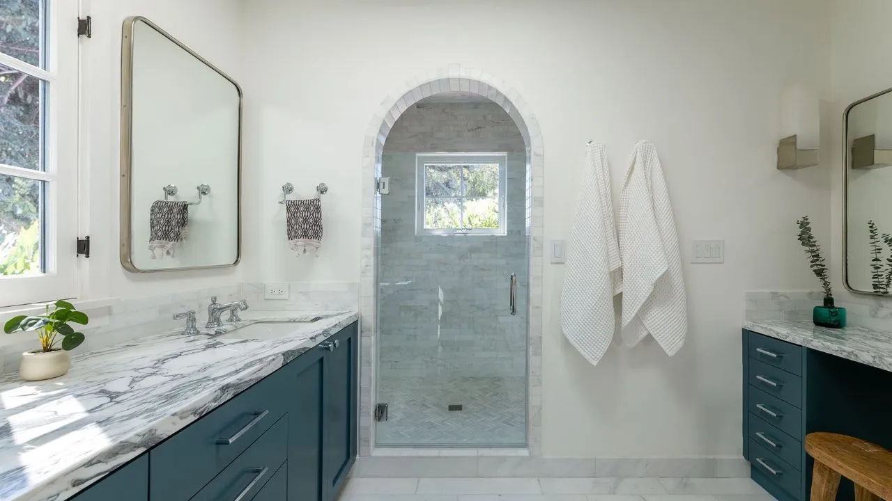 Um banheiro branco com pia em azul escuro e bancada de mármore' loading='lazy' title=