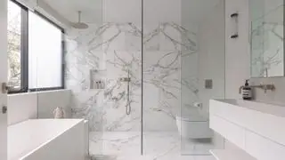 Banheiro de mármore com box amplo e banheira vitoriana