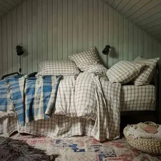 Literie en lin à carreaux neutres sur un lit double empilé de coussins
