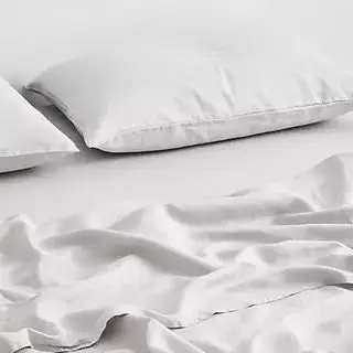 Un drap plat blanc et une taie d'oreiller sur fond blanc