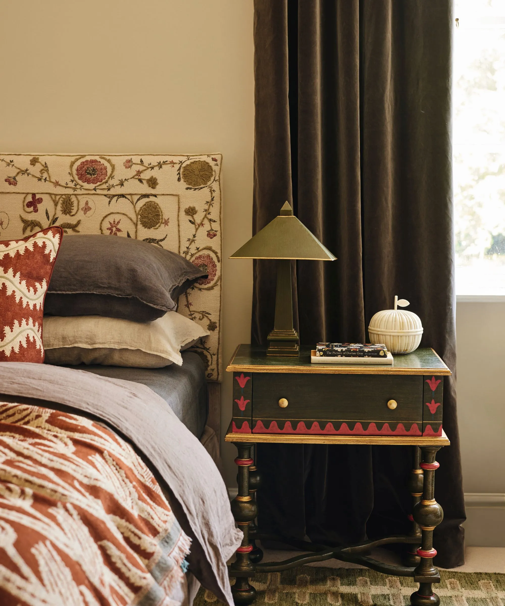 Neutralna sypialnia z wzorzystym zagłówkiem i malowanym stolikiem bocznym.' loading='lazy' title=