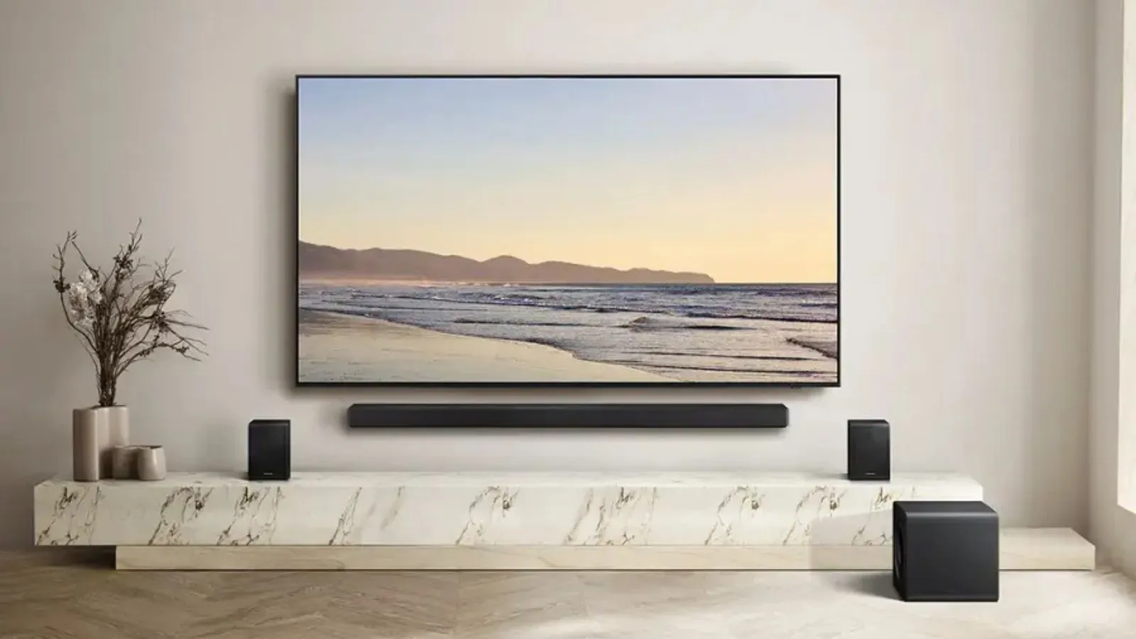 サムスン HW-QS750F サウンドバー ウーファーとサラウンド スピーカーは、植物の隣の大理石のスタンドのテレビの周りの静かなリビング ルームにあります。' loading='lazy' title=