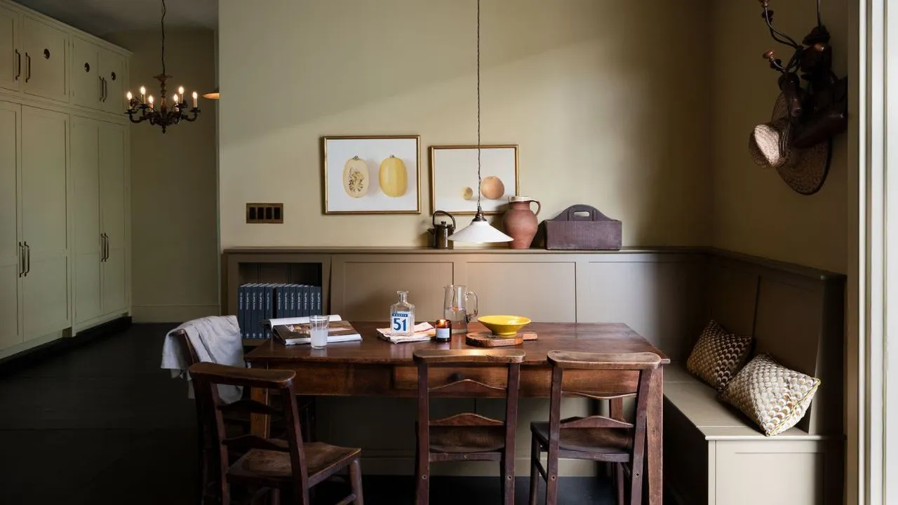 Canto de jantar cinza claro com bancos em forma de L em pintura cinza escuro, mesa de madeira de meados do século com quatro cadeiras de jantar e armários embutidos do chão ao teto à esquerda' loading='lazy' title=