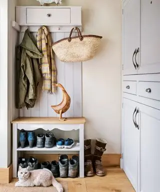 Un mudroom con deposito per scarpe in una panca, un pensile e armadietti grigi a tutta parete