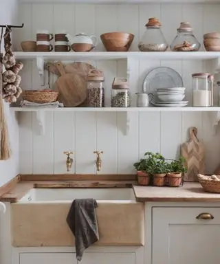 Scaffali rustici aperti sopra un lavello in gres in una cucina bianca