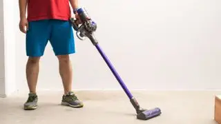 Um homem limpando um piso de madeira com o Dyson V8 Animal.