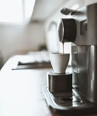 Una taza de café llena en una cafetera