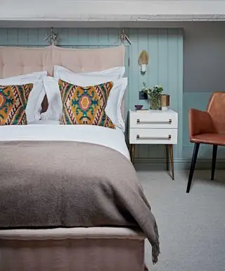 dormitorio con cama, almohadas y mesita de noche