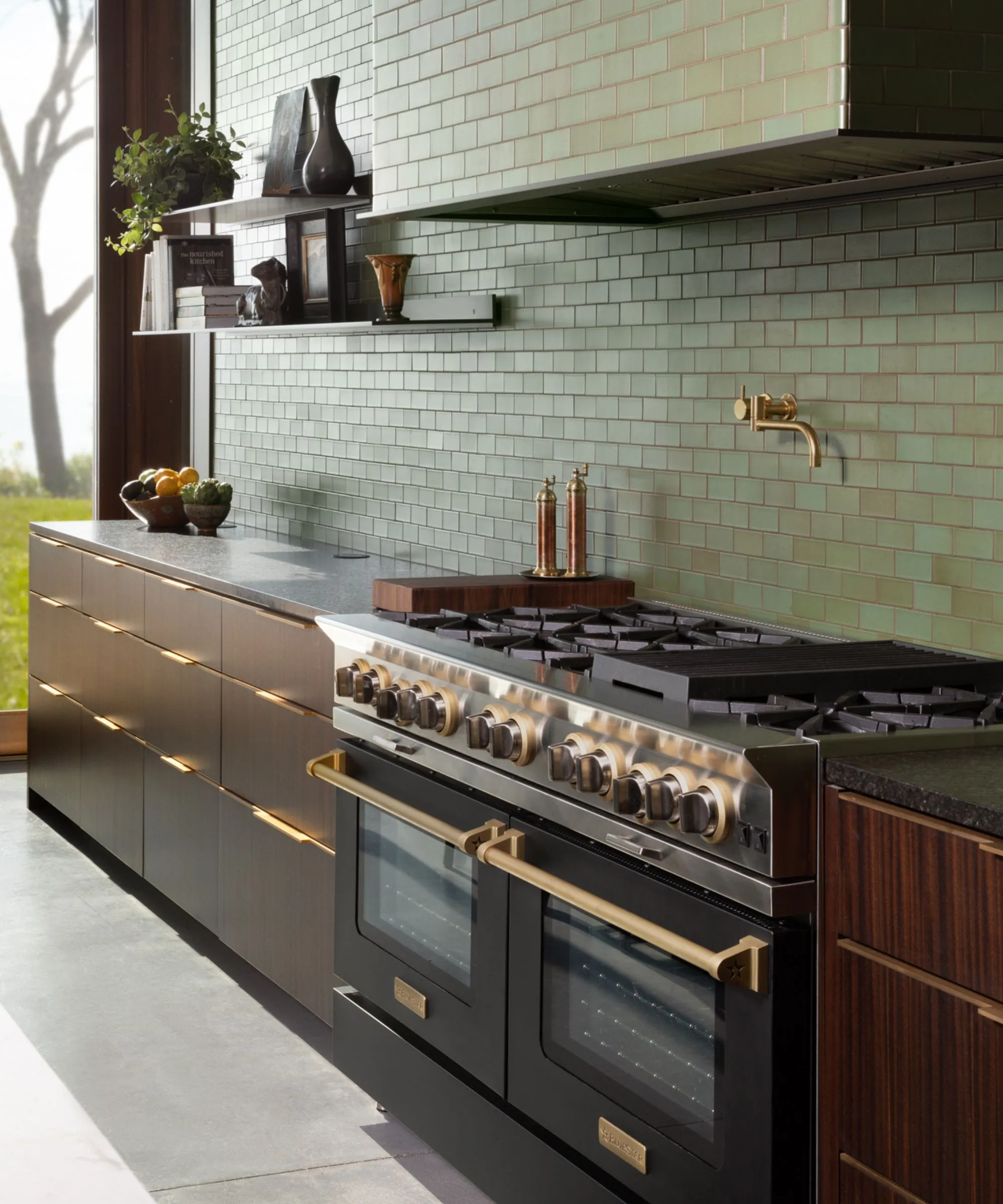 Una cucina piastrellata verde della metropolitana con mobili in legno scuro e una doppia stufa nera.' loading='lazy' title=