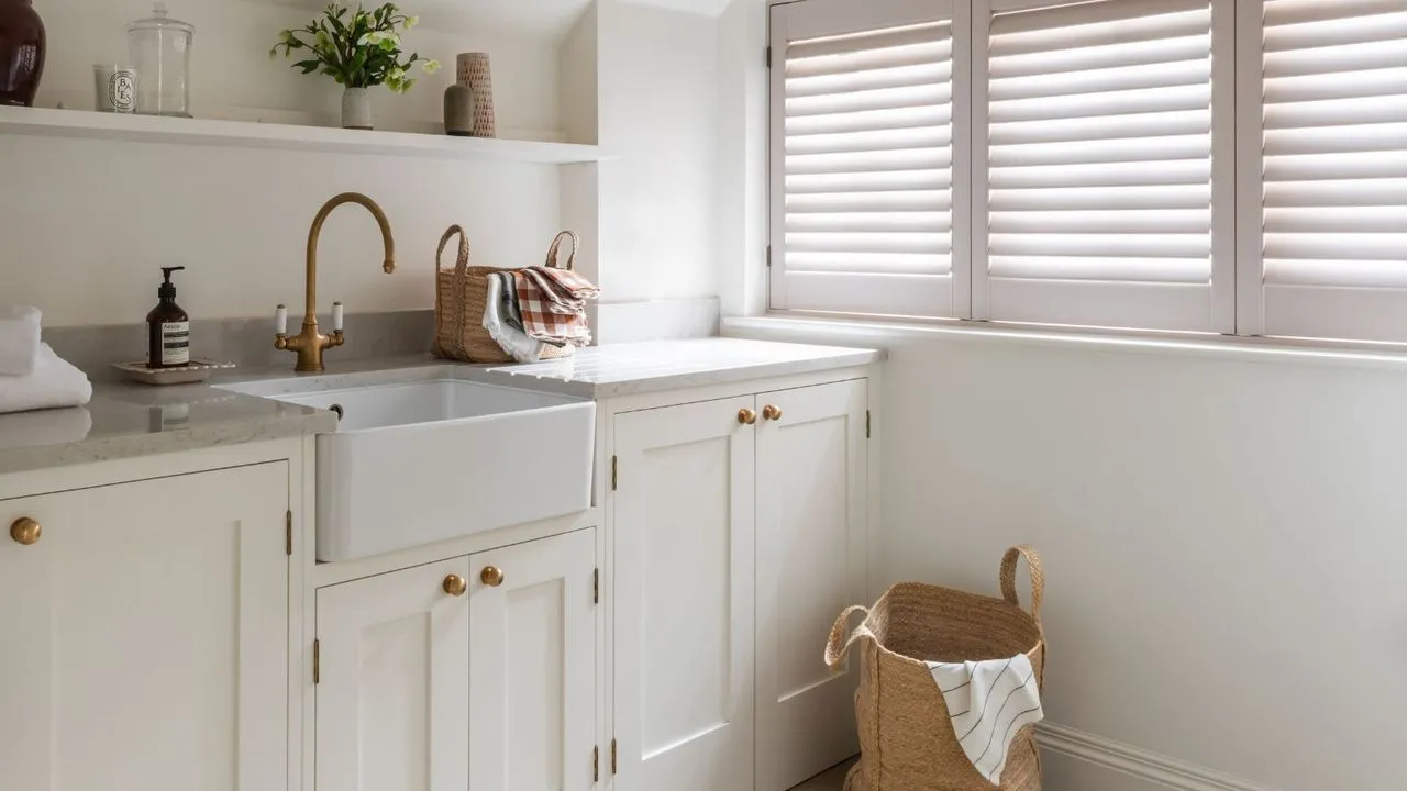 Světlá neutrální prádelna s okenicemi a tkaným košem' loading='lazy' title=