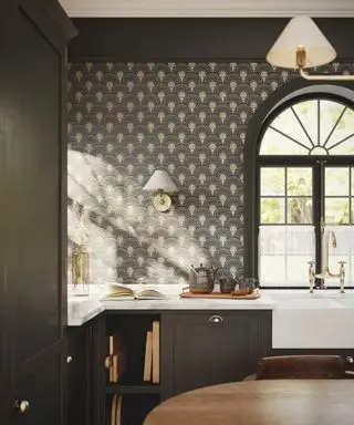 Shaker-Küche mit braunen Schränken, Tapete im Art-Deco-Stil, Bogenfenster, Marmorarbeitsplatten, Spüle, Wandleuchten und passender Pendelleuchte, Tisch